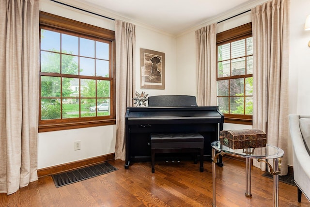 living area with wood finished floors, crown molding, and baseboards