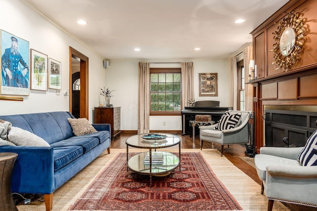 living room featuring wood finished floors, crown molding, a fireplace, recessed lighting, and baseboards