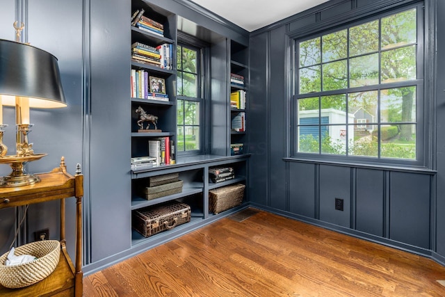 sitting room with wood finished floors and built in shelves