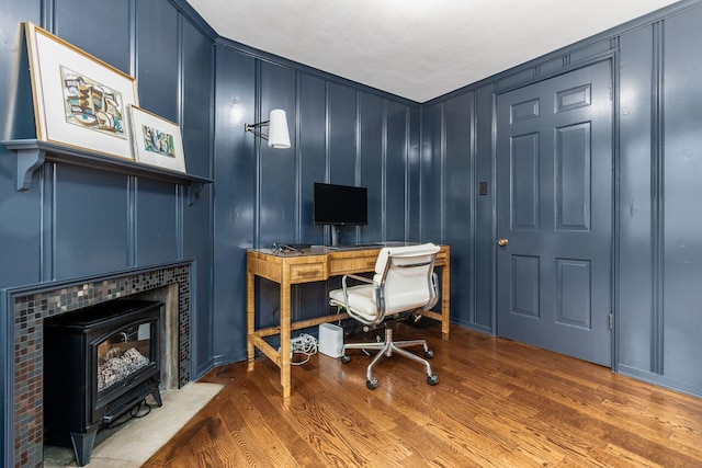 office area featuring a decorative wall, wood finished floors, and a wood stove