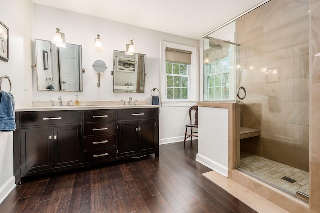 full bathroom with hardwood / wood-style flooring, baseboards, a shower stall, and double vanity