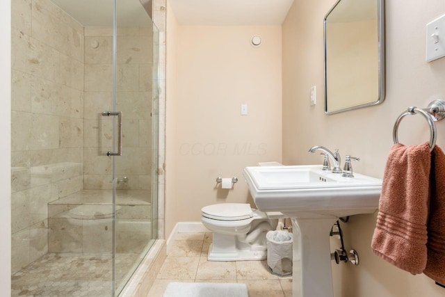bathroom with toilet, a shower stall, baseboards, and tile patterned floors