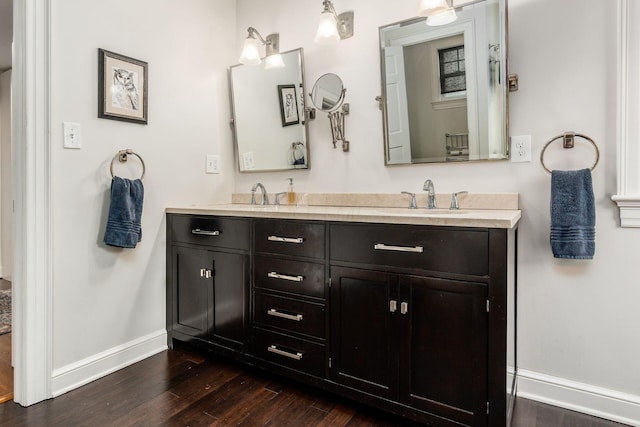 bathroom with baseboards, hardwood / wood-style floors, and double vanity
