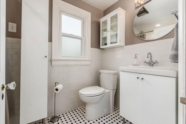 bathroom with tile walls, toilet, wainscoting, and vanity