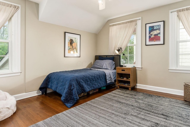 bedroom with wood finished floors, multiple windows, baseboards, and vaulted ceiling