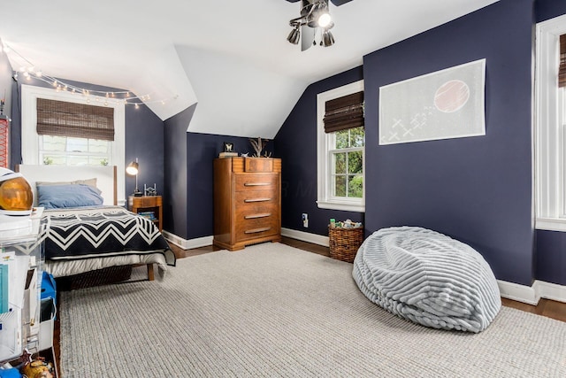 bedroom with multiple windows, baseboards, wood finished floors, and lofted ceiling
