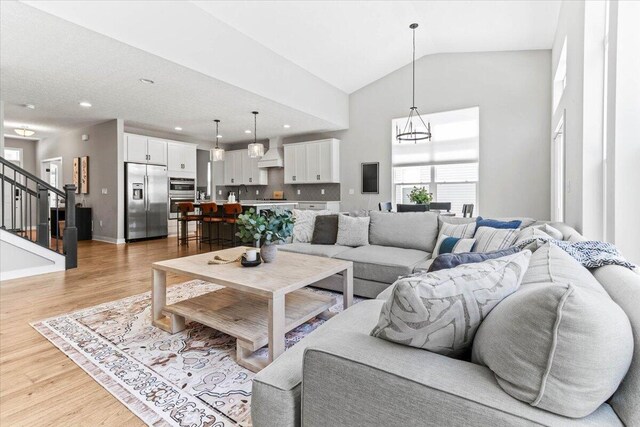 9129 Coe Dr, Plain City, OH 43064 - living area with light wood-type flooring, stairs, high vaulted ceiling, a chandelier, and recessed lighting