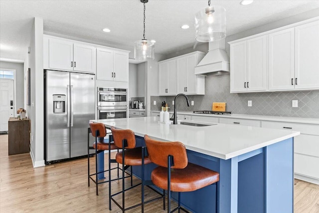 9129 Coe Dr, Plain City, OH 43064 - kitchen featuring appliances with stainless steel finishes, a sink, tasteful backsplash, a center island with sink, and light wood-style floors