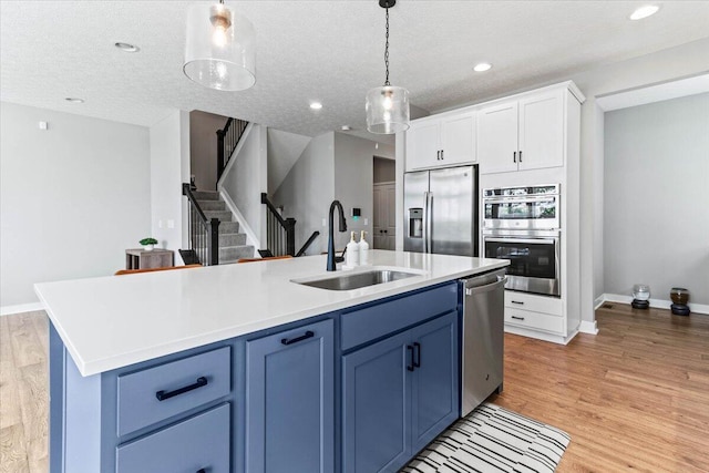 9129 Coe Dr, Plain City, OH 43064 - kitchen with appliances with stainless steel finishes, a sink, blue cabinetry, a center island with sink, and recessed lighting