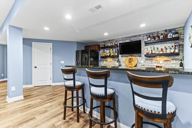 9129 Coe Dr, Plain City, OH 43064 - indoor wet bar with black fridge with ice dispenser, light wood finished floors, recessed lighting, and baseboards