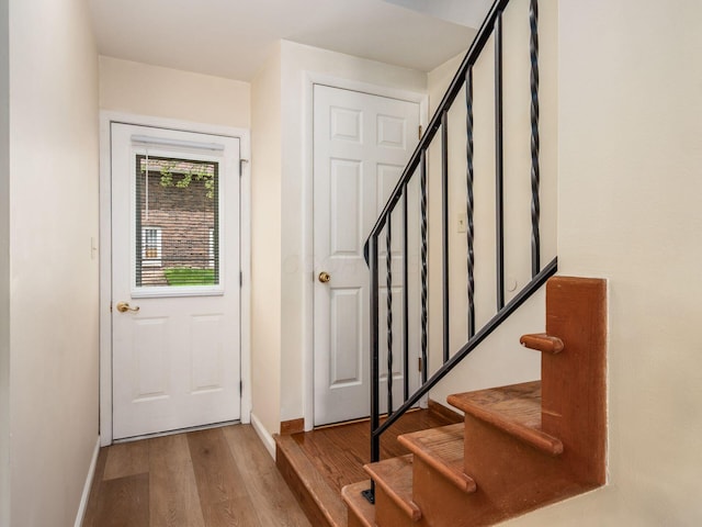 doorway to outside with wood finished floors, baseboards, and stairs