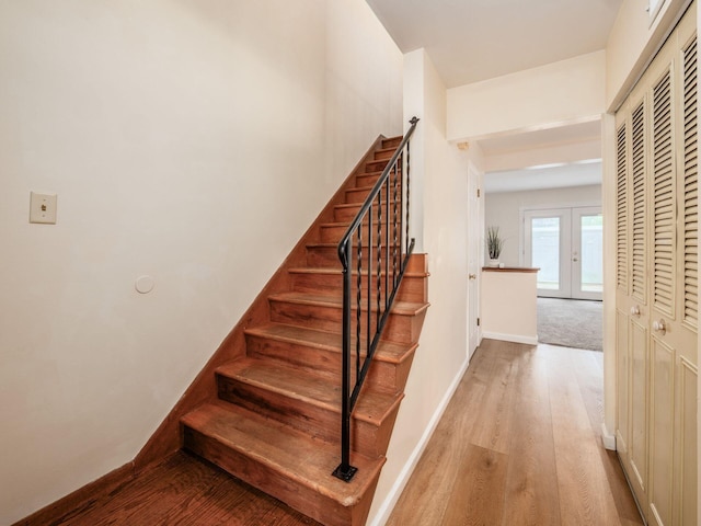 staircase featuring wood finished floors, baseboards, and french doors