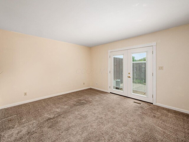 carpeted empty room featuring baseboards and french doors