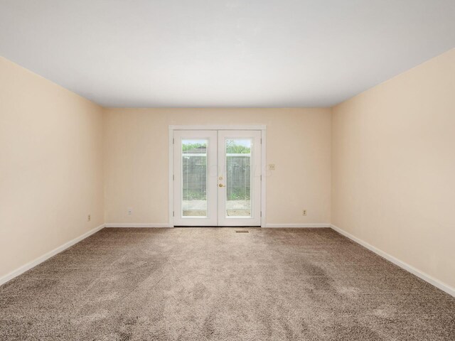 empty room featuring french doors, carpet, and baseboards
