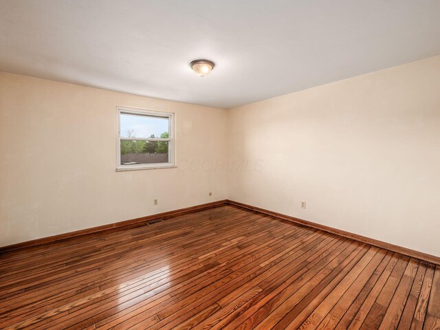 empty room featuring hardwood / wood-style floors and baseboards
