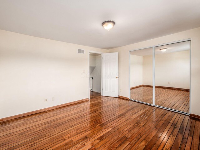 unfurnished bedroom with wood-type flooring, baseboards, and a closet