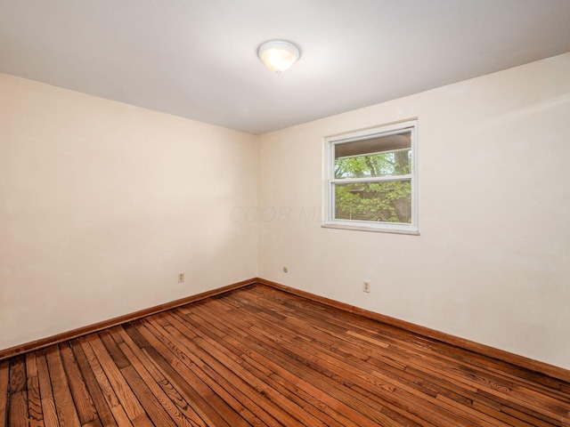 empty room featuring dark wood-type flooring and baseboards