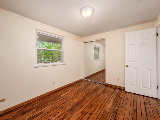 spare room featuring wood-type flooring, plenty of natural light, and baseboards