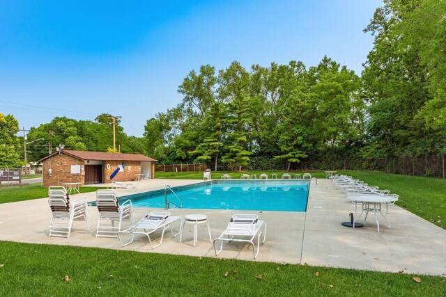 community pool with a patio and view of wooded area