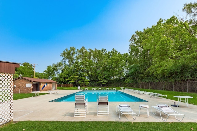community pool with a patio area and fence