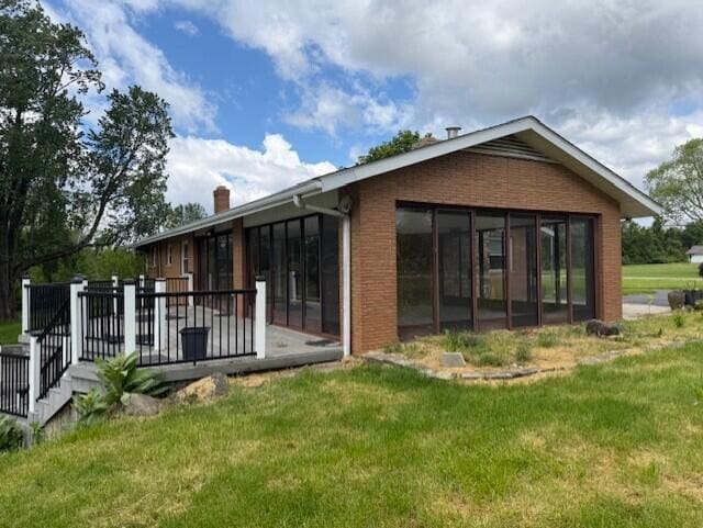 8165 Busey Rd, Pickerington, OH 43147 - rear view of house featuring a yard, a chimney, a wooden deck, and a sunroom