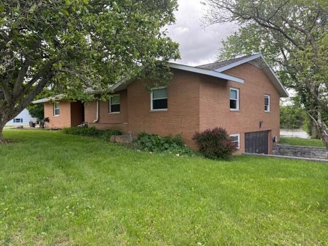 8165 Busey Rd, Pickerington, OH 43147 - view of side of home featuring a garage, brick siding, a lawn, and driveway