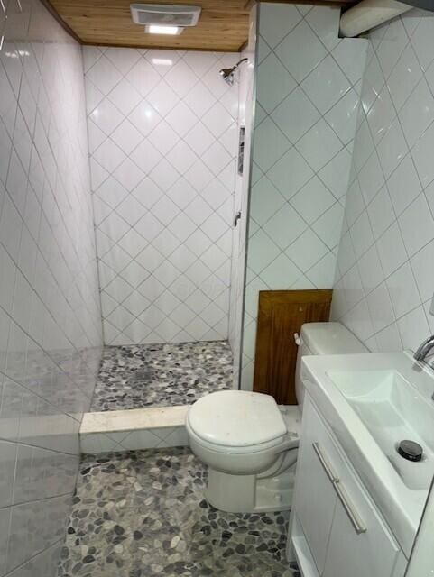 8165 Busey Rd, Pickerington, OH 43147 - bathroom featuring tiled shower, toilet, vanity, and tile walls