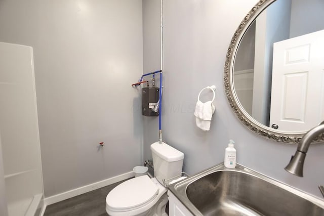 bathroom featuring toilet, wood finished floors, baseboards, and a sink