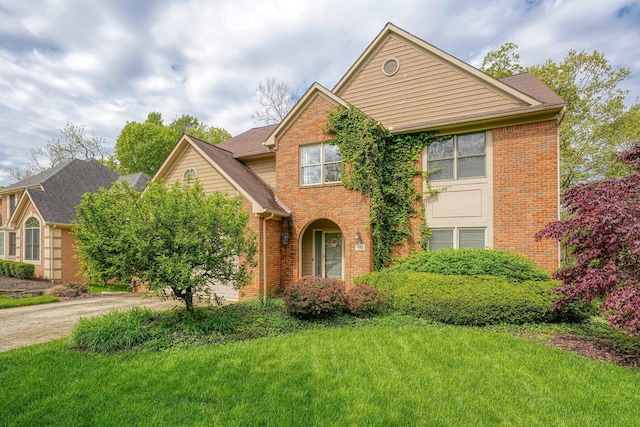traditional-style house featuring concrete driveway, brick siding, and a front yard