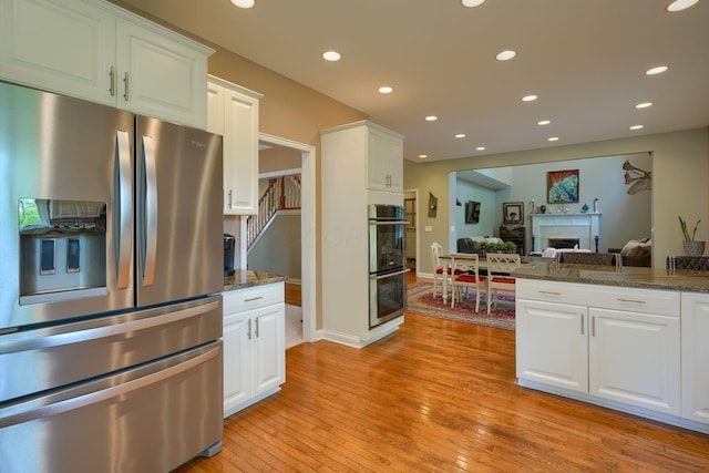 kitchen featuring light wood finished floors, stainless steel appliances, white cabinetry, and recessed lighting