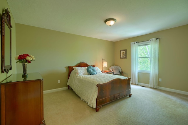 bedroom with light colored carpet and baseboards