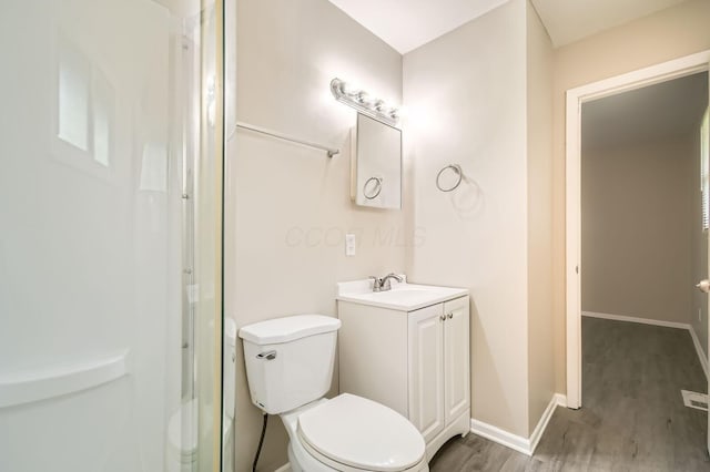 full bathroom featuring wood finished floors, a shower, toilet, baseboards, and vanity