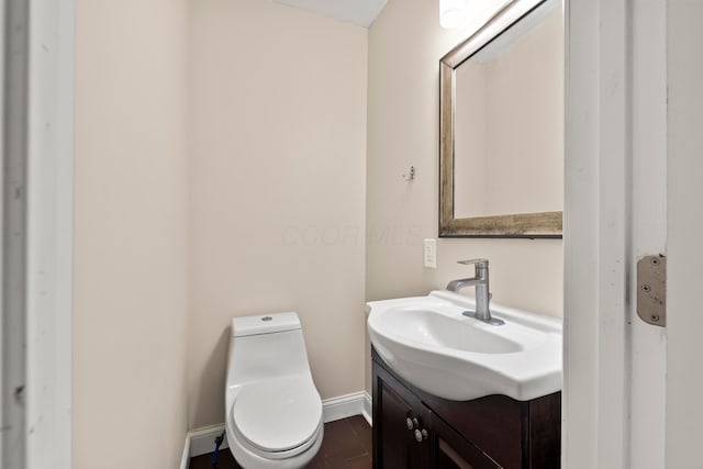 half bath with vanity, toilet, and baseboards