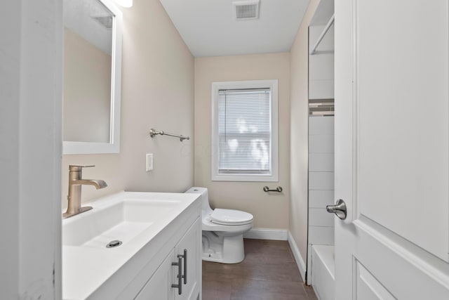 bathroom with toilet, vanity, wood finished floors, and baseboards