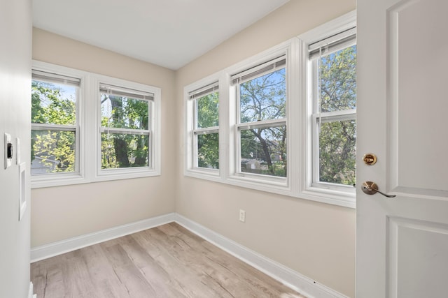 spare room featuring baseboards, healthy amount of natural light, and light wood finished floors