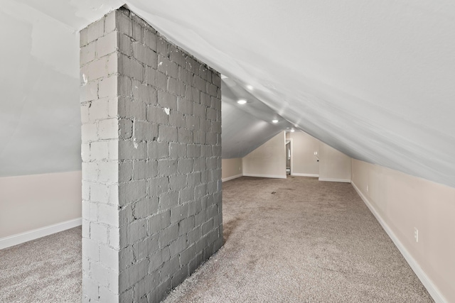 additional living space featuring lofted ceiling, carpet floors, concrete block wall, and baseboards