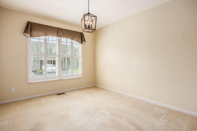 carpeted spare room with a chandelier and baseboards