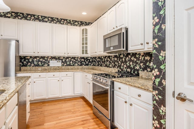 kitchen featuring stainless steel appliances, light wood-style flooring, white cabinets, light stone counters, and recessed lighting