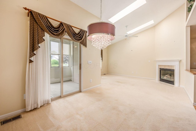 unfurnished living room featuring carpet, a high end fireplace, a skylight, a chandelier, and baseboards