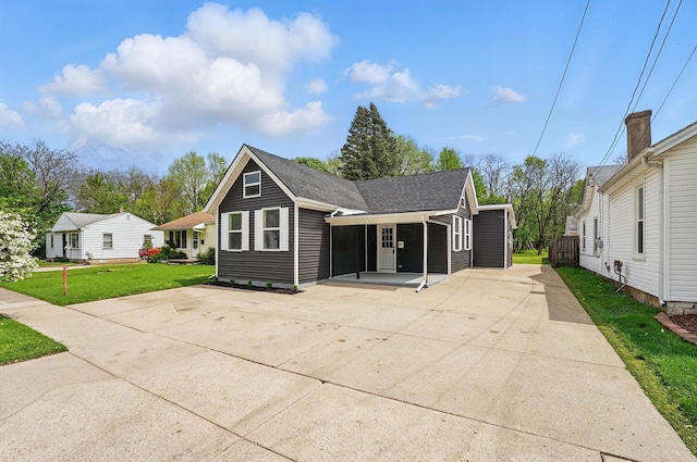 view of front of property featuring driveway, a shingled roof, and a front yard
