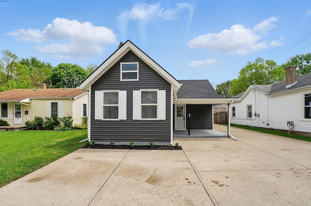 back of house with concrete driveway and a lawn