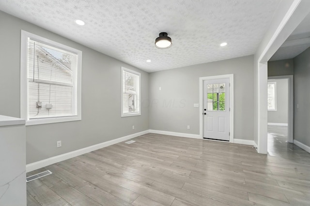 entryway with light wood-style flooring, a textured ceiling, visible vents, baseboards, and recessed lighting