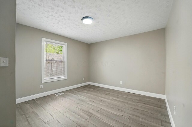 unfurnished room featuring a textured ceiling, baseboards, and wood finished floors