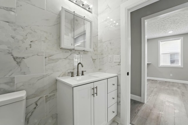 bathroom with tile walls, toilet, and vanity