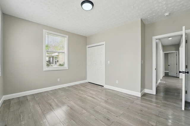 unfurnished bedroom with baseboards, a textured ceiling, and wood finished floors