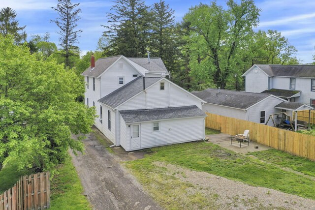 233-235 N 13th St, Newark, OH 43055 - view of home's exterior featuring a patio area, a shingled roof, a chimney, and asphalt driveway