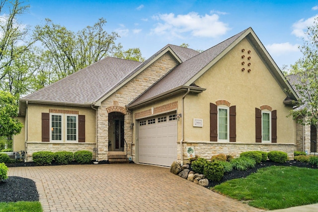 5464 Slater Rdg, Westerville, OH 43082 - view of front of house with stone siding, a garage, stucco siding, and decorative driveway