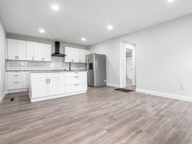 3147 Grasmere Ave, Columbus, OH 43224 - kitchen with wall chimney exhaust hood, white cabinetry, stainless steel fridge, backsplash, and baseboards