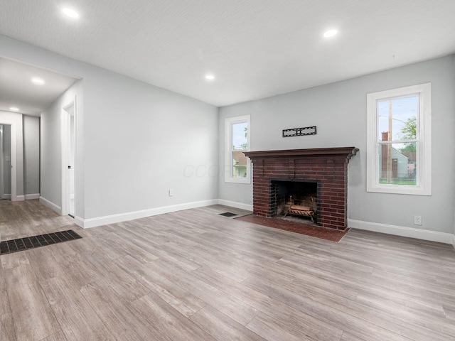 3147 Grasmere Ave, Columbus, OH 43224 - unfurnished living room with baseboards, a brick fireplace, visible vents, and wood finished floors