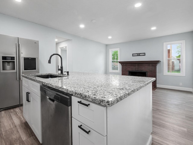 3147 Grasmere Ave, Columbus, OH 43224 - kitchen featuring a sink, light stone counters, light wood-type flooring, white cabinets, and appliances with stainless steel finishes